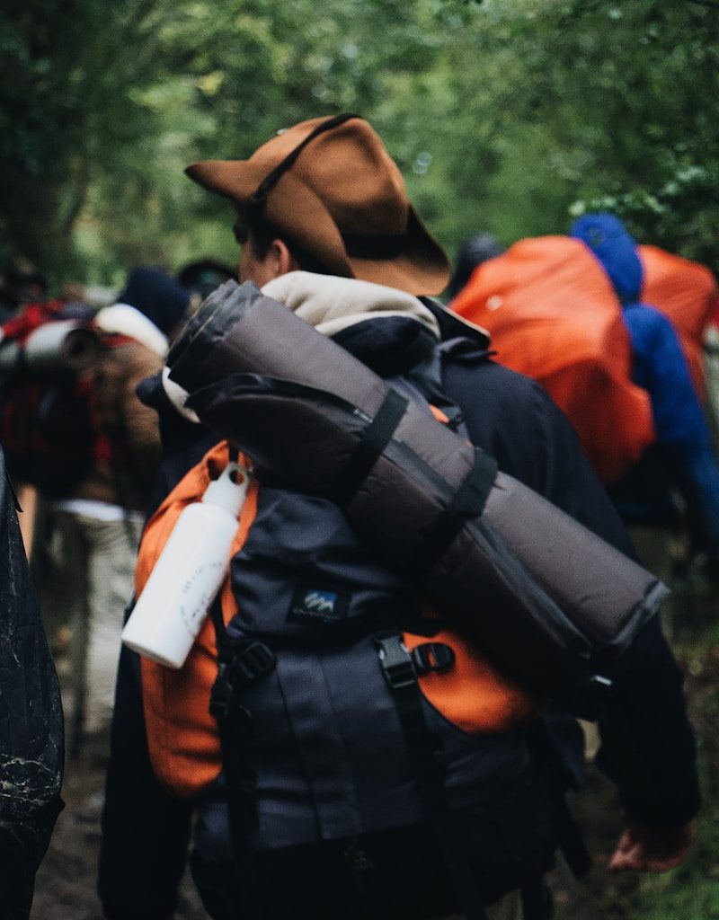 man carrying black sleeping bag and backpack
