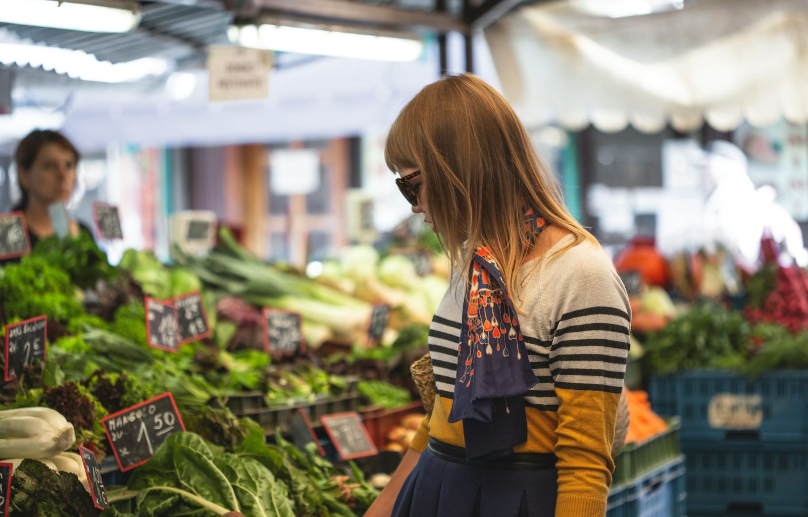 woman standing in front of vegetables in market during day time