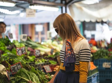 woman standing in front of vegetables in market during day time