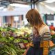 woman standing in front of vegetables in market during day time