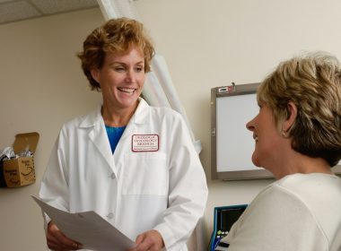 woman in white scrub suit holding gray laptop computer