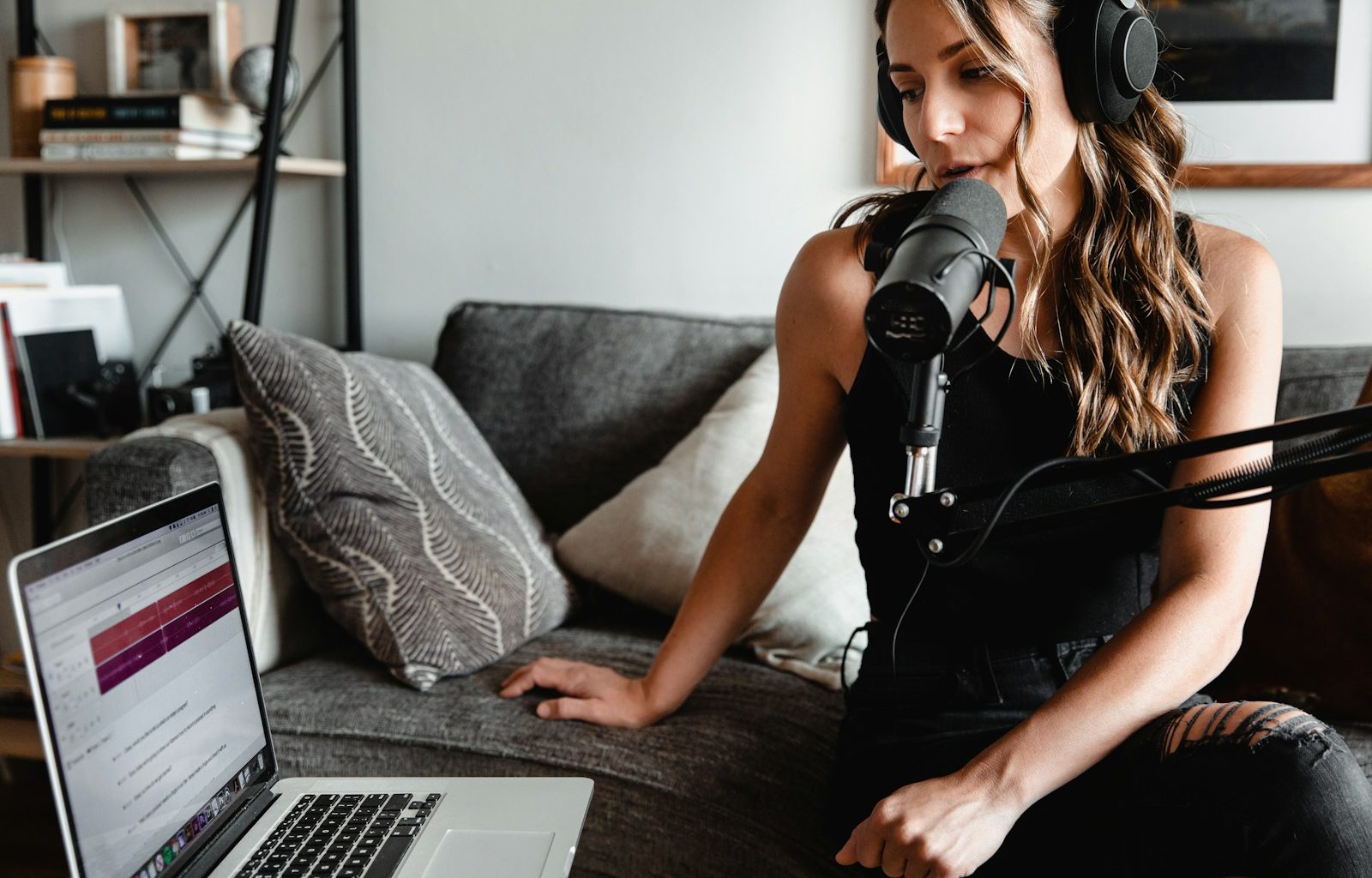 woman in black tank top sitting on couch using macbook