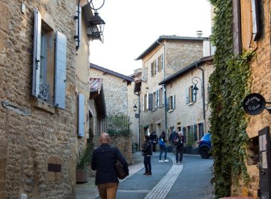 A woman walking down a street next to tall buildings