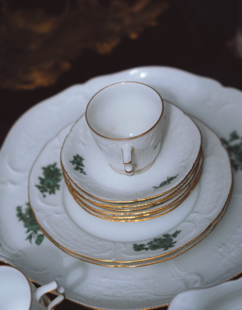a stack of white and gold china plates