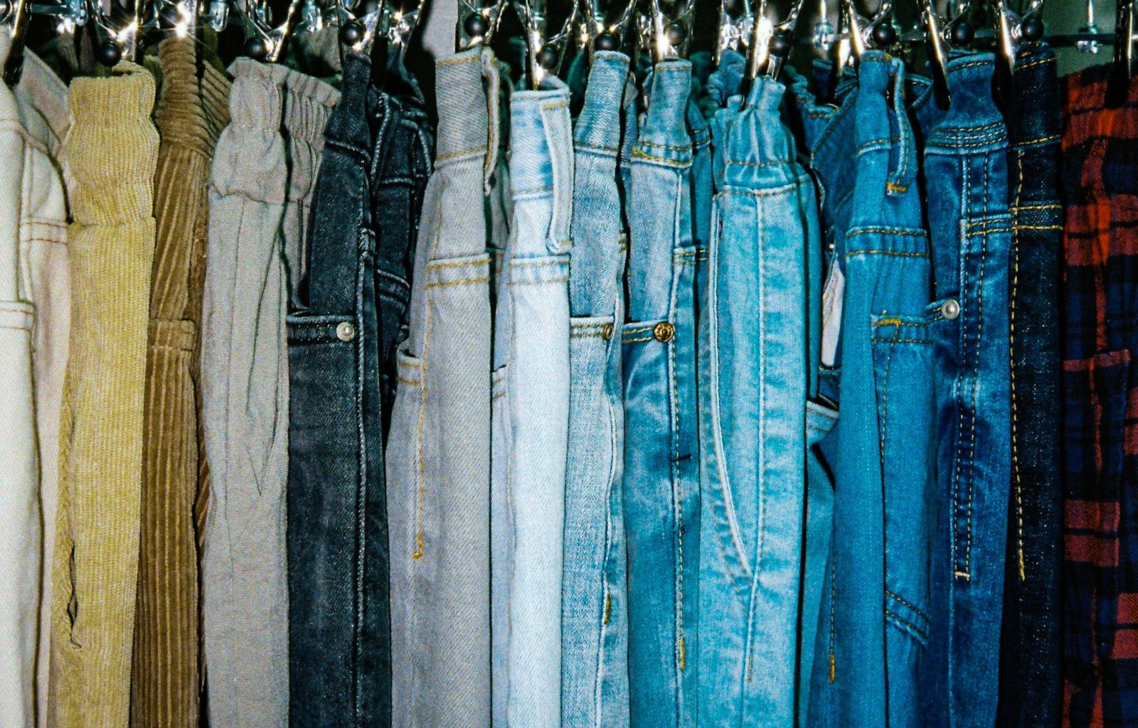 a rack of different colored jeans hanging from hooks