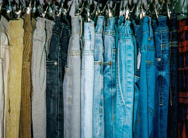 a rack of different colored jeans hanging from hooks