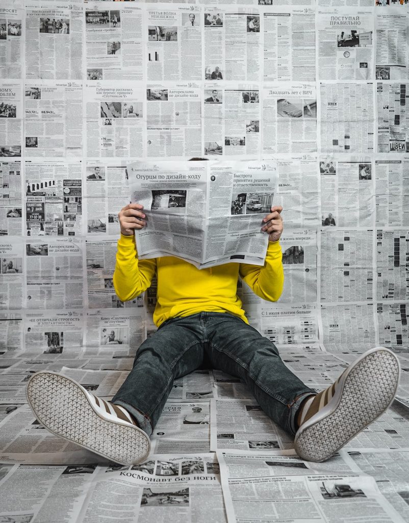 a person sitting on the floor reading a newspaper