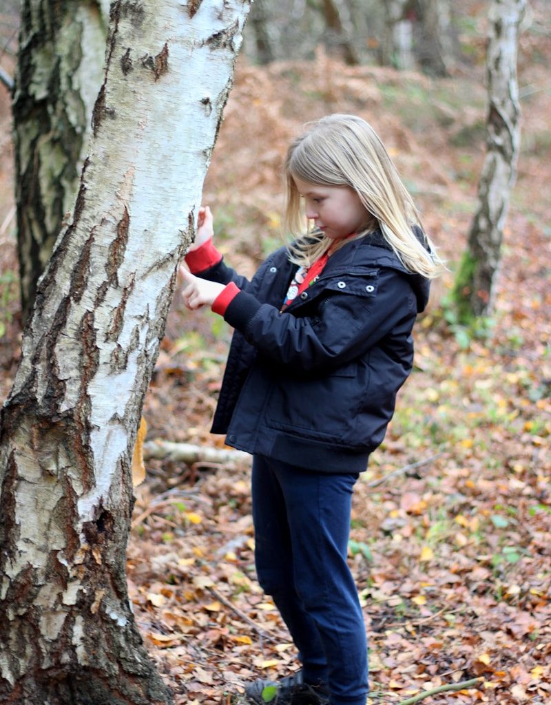 woman in black jacket and black pants standing beside tree