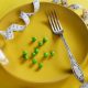 a plate with a fork, measuring tape and green peas