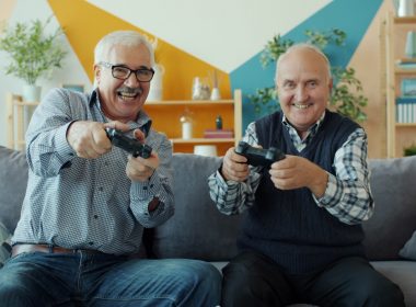 Two smiling elderly men playing video games together.