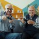 Two smiling elderly men playing video games together.