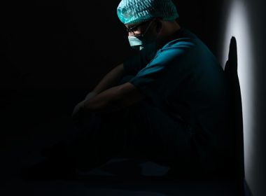 man in green shirt and blue knit cap sitting on floor