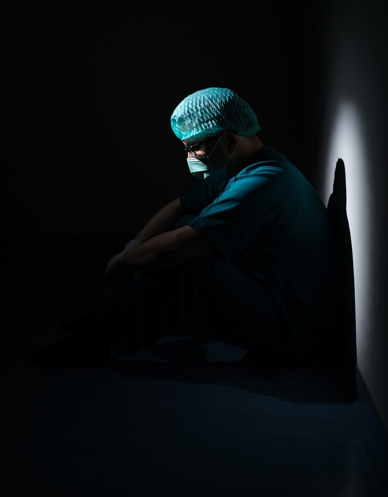 man in green shirt and blue knit cap sitting on floor