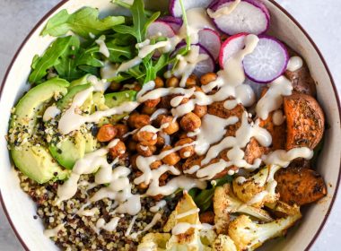 a bowl filled with vegetables and dressing next to a glass of milk