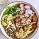 a bowl filled with vegetables and dressing next to a glass of milk