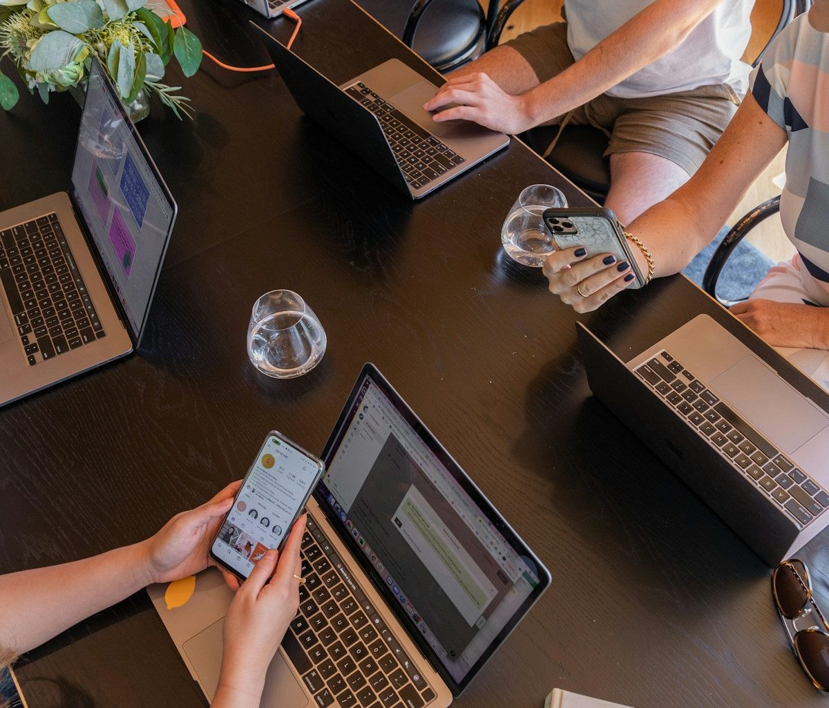 a group of people sitting around a table with laptops