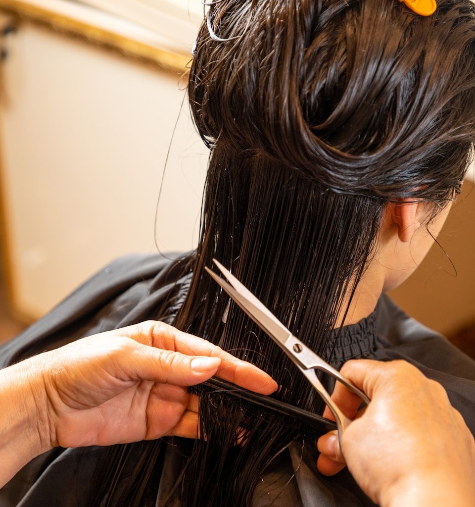 a woman cutting another woman's hair with scissors