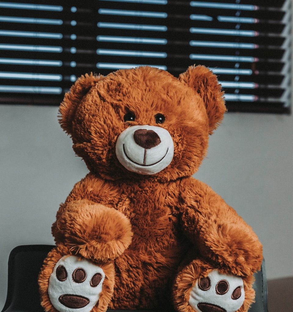 a brown teddy bear sitting on top of a desk