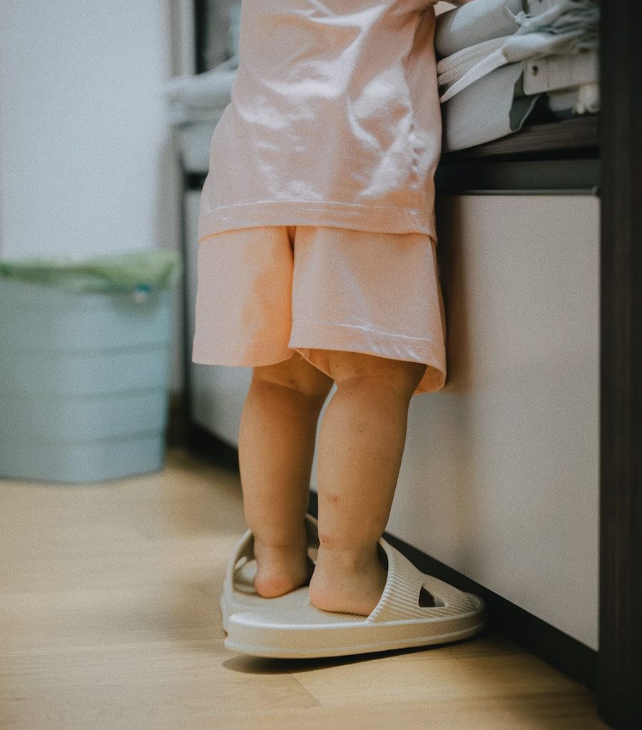 Toddler wearing oversized slippers stands by counter.