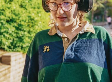 Portrait of a nonbinary autistic person outdoors using headphones