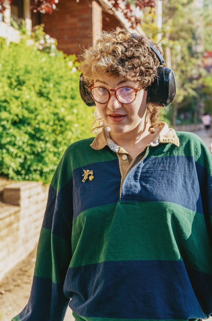Portrait of a nonbinary autistic person outdoors using headphones