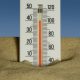 A thermometer in the sand with a blue sky in the background