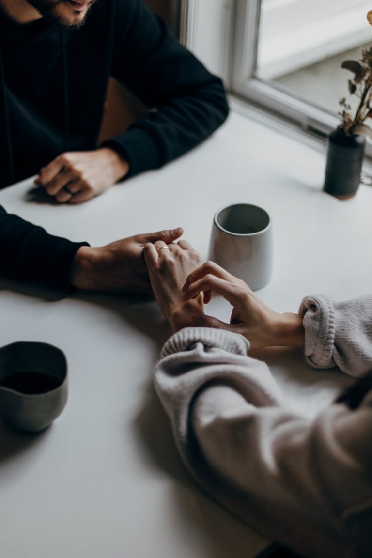 two people holding hands at table