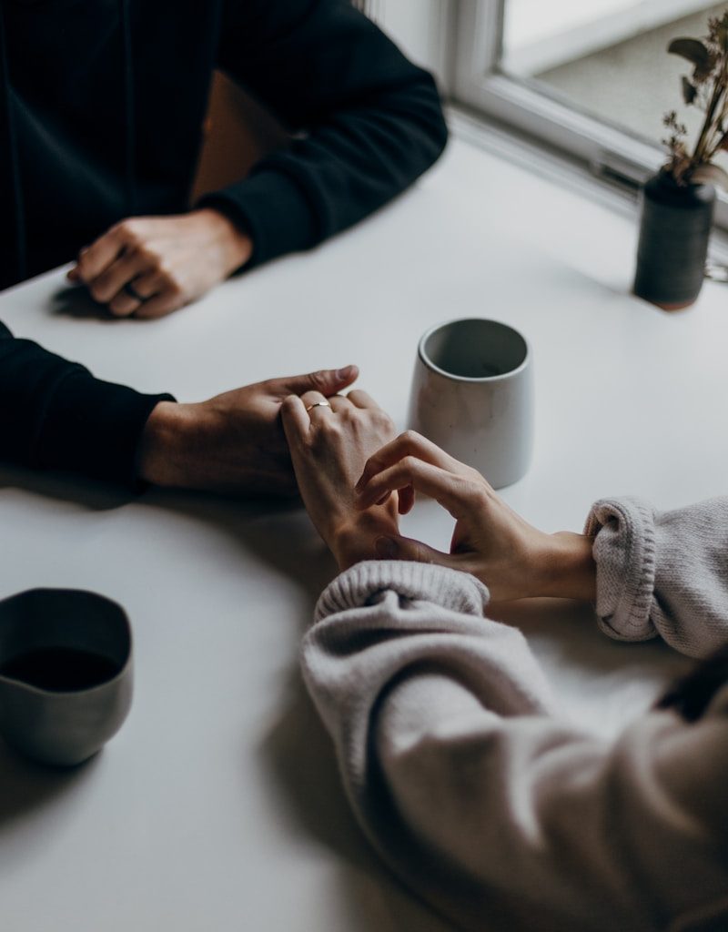 two people holding hands at table