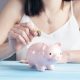 woman in white tank top holding pink pig figurine