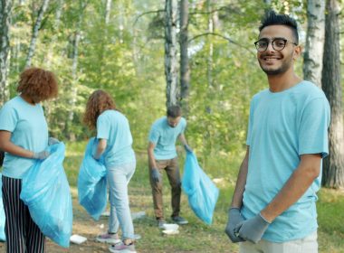 Volunteers cleaning a park with blue trash bags