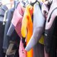 A row of colorful wetsuits hanging on a rack outdoors
